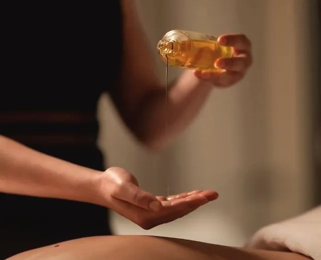 Óleo de massagem a ser vertido na mão da terapeuta